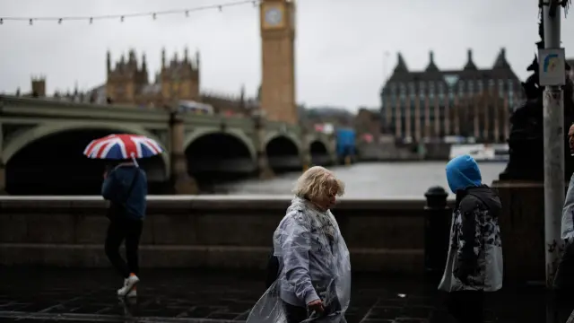 London (United Kingdom), 28/03/2024.- People walk along the Southbank against strong winds in the rain with The Palace of Westminster, home to the Houses of Parliament, in the background, in London, Britain, 28 March 2024. The UK Met Office has issued a yellow warning as Storm Nelson brings heavy rain and gusts as high as 70mph (112 km h) to southern and eastern England ahead of the Easter weekend. (tormenta, Reino Unido, Londres) EFE/EPA/TOLGA AKMEN