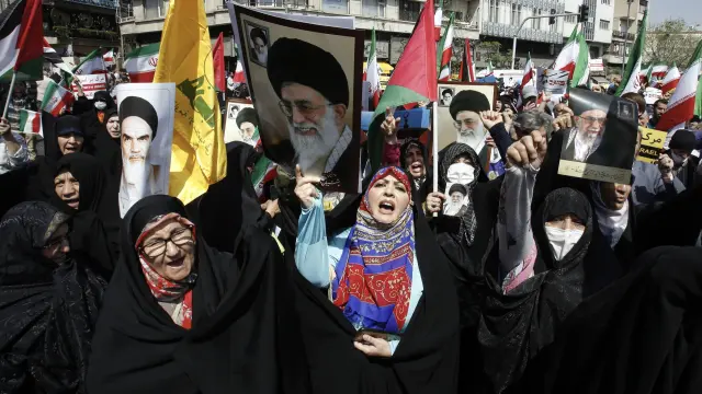 Tehran (Iran(islamic Republic Of)), 19/04/2024.- Iranian women hold up portraits of the Iranian supreme leader Ayatollah Ali Khamenei and and former supreme leader Ruhollah Khomeini (L) as others wave Iranian and Palestinian flags during an anti-Israel rally in Tehran, Iran, 19 April 2024. Iranian state media reported that three aerial objects were destroyed by air defense systems over the central city of Isfahan early morning on 19 April. The explosions come after a drone and missile attack carried by Iran's Islamic Revolutionary Guards Corps (IRGC) towards Israel on 13 April, following an airstrike on the Iranian embassy in Syria which Iran claimed was conducted by Israel. (Siria, Teherán) EFE/EPA/ABEDIN TAHERKENAREH