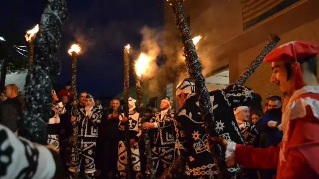 Contradanceros con trajes tradicionales y hachas encendidas, junto al diablo de rojo, durante la celebración de la contradanza en Cetina, creando una atmósfera mágica y deslumbrante.