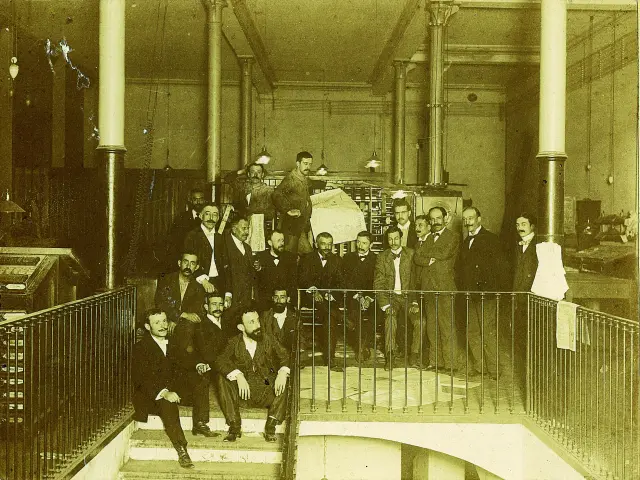 Darío Pérez, en el centro con bigote fino, barba y la pierna cruzada, con los integrantes de la redacción de El Liberal en Barcelona junto a la rotativa en 1901.