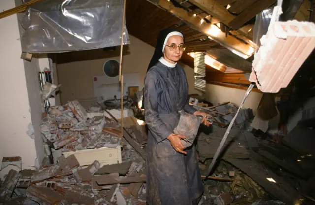 Una monja católica muestra los restos del proyectil que destrozó su vivienda en otoño de 1991