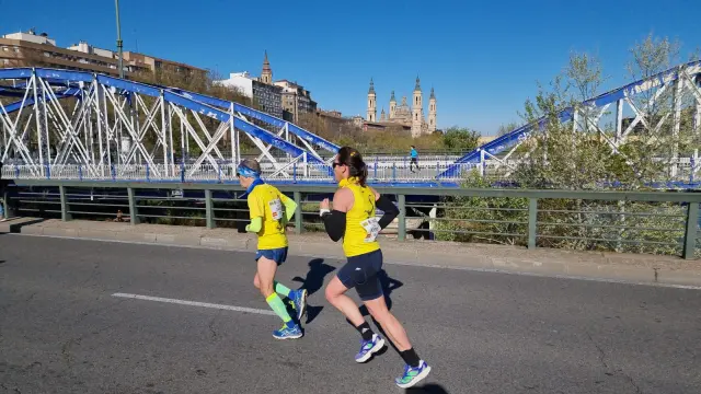 Ana Buero y José Antonio Sayas cruzan el puente de Hierro, durante el Maratón de Zaragoza.