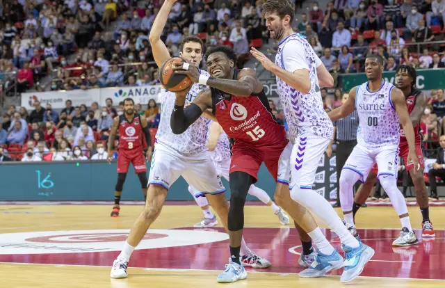El jugador del Casademont Zaragoza Mekowulu (c) intenta pasar ante los jugadores del Bilbao Basket Reyes (i) y Withey (d) durante el partido de Liga Endesa uque disputan en el pabellón Príncipe Felipe de ZAragoza.