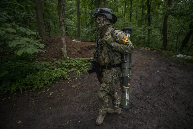 El soldado Vinin carga con un lanzagranadas cerca de una trinchera en medio de un bosque en Ucrania.