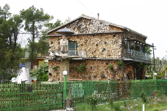 La vista de la casa, con el tótem y las cerámicas en la verja, desde la carretera que conduce a Salas.