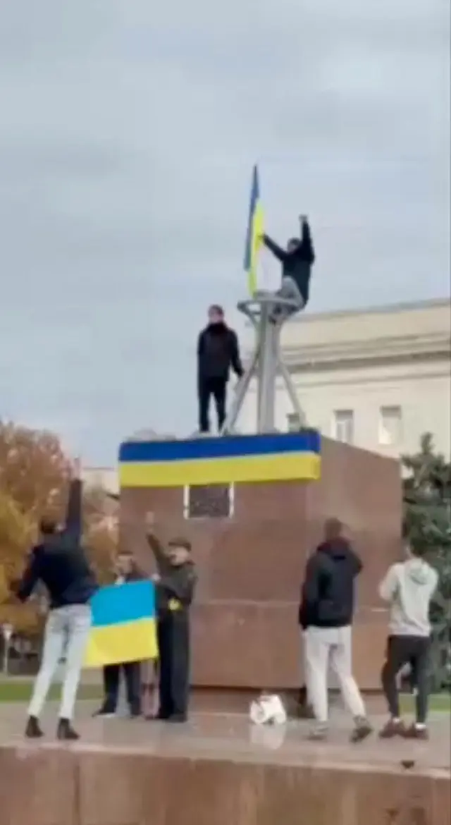 Un grupo de ciudadanos coloca la bandera ucraniana en una céntrica plaza de Jersón