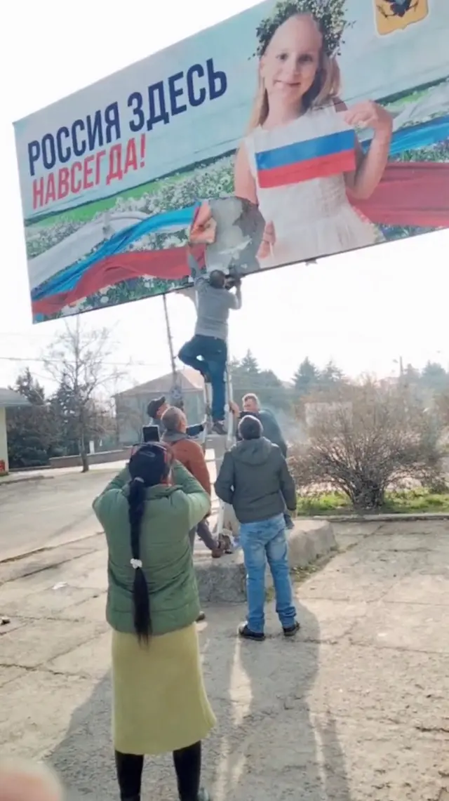 Un hombre arranca un cartel ruso en la región de Jersón