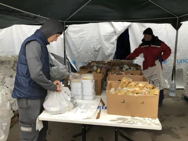 Dos voluntarios preparan bolsas con productos enlatados