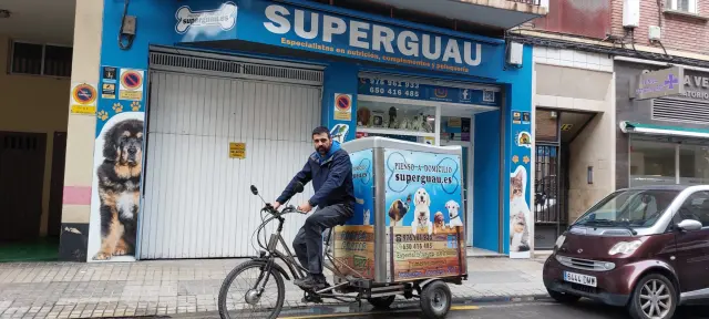 Jorge Estrada, copropietario de Superguau, con la bicicleta en la que reparte el pienso a domicilio.