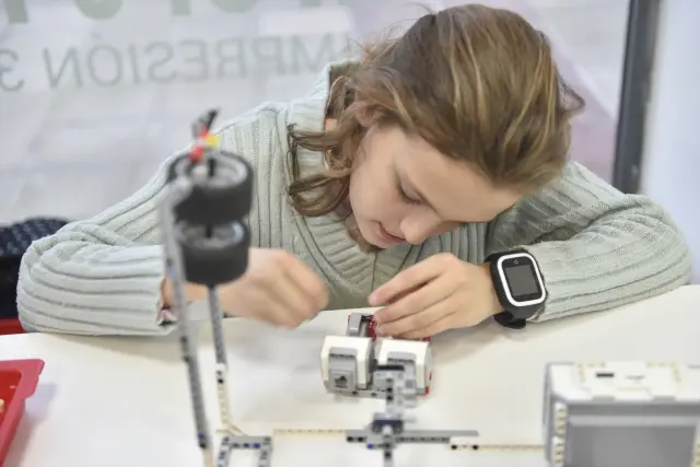 Una niña aprende a montar las piezas de un pequeño robot.
