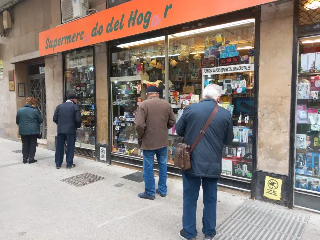 Gente mirando es escaparate de la tienda el 'Supermercado del Hogar' en la calle de San Miguel de Zaragoza.