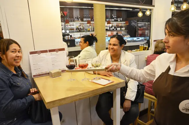 La camarera ofrece los vinos a dos clientas en La Gerencia del Tubo
