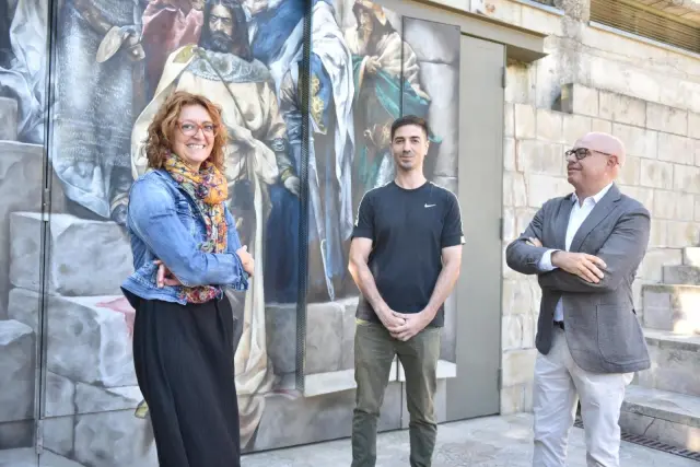 Laura Asín, Edd Bhurton y Fernando Sarría, junto al mural que reproduce el cuadro de 'La Campana de Huesca' en la plaza de General Alsina.