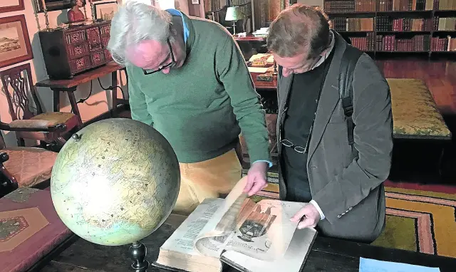 Pío Caro-Baroja, con José Luis Melero, hojeando unos manuales ante la bola del mundo.