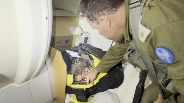 Un oficial israelí señala lo que describe como una bolsa que contiene un rifle y otras municiones pertenecientes a un combatiente de Hamás que fue descubierta detrás de una máquina de resonancia magnética en el complejo hospitalario de Al Shifa