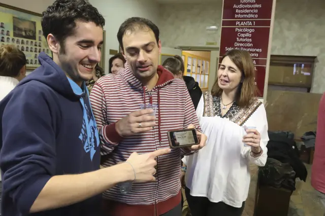 Agraciados con el Gordo repartido por la Asociación de Antiguos Alumnos del colegio San Viator de Huesca muestran una foto de la participación premiada en el móvil.
