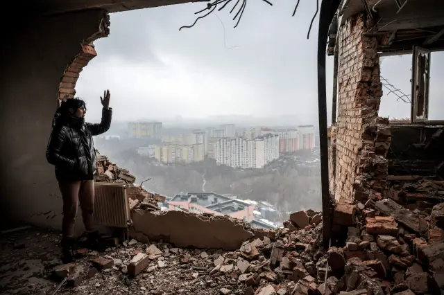 Una mujer mira una ciudad ucraniana en un edificio dañado por la guerra.