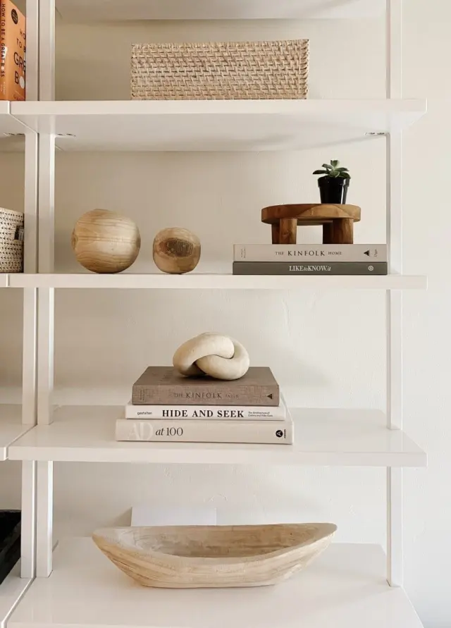 Una estantería con varias piezas de cerámica, libros y una cestita.