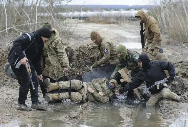 Ucranianos evacuan a un hombre que simula estar herido durante un entrenamiento militar para civiles organizado por el 'sector derecho' cerca de la ciudad ucraniana occidental de Lviv