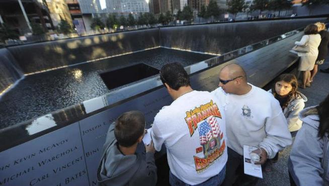Varias personas participan en una ceremonia para conmemorar a las víctimas de los atentados terroristas de 2001 en el lugar donde se encontraba el World Trade Center
