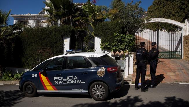 Dos miembros de la Policía Nacional custodian la vivienda donde anoche una mujer de 58 años y de nacionalidad española fue asesinada a puñaladas por su pareja en Estepona (Málaga).