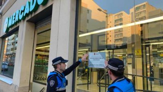 Agentes de policía colocan un cartel en un supermercado