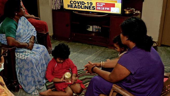 Una familia de Bangalore escucha el discurso del primer minsitro Modi sobre el Covid-19 en televisión.