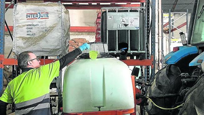 Un cooperativista de la Cooperativa Agrícola San Miguel espera que carguen su atomizador con lejía y agua.