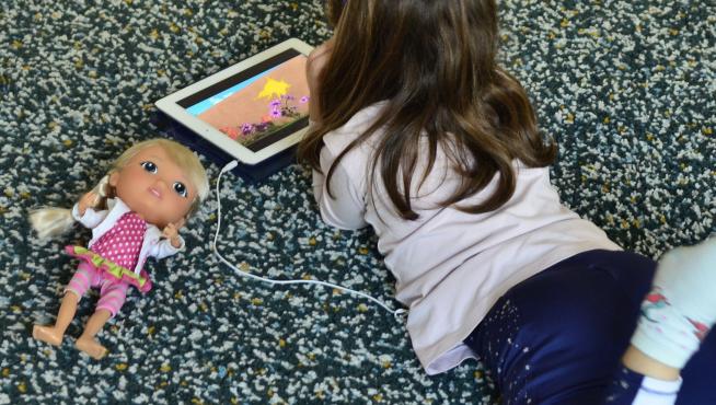 Una niña mirando unos dibujos durante el confinamiento en Valencia.