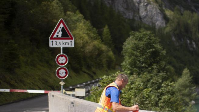 Un operario pone un cartel de aviso en la carretera que lleva a la zona del accidente.