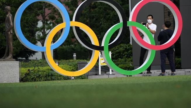 Un hombre se toma fotos con los aros olímpicos junto al estadio donde se debían celebrar este año los juegos.