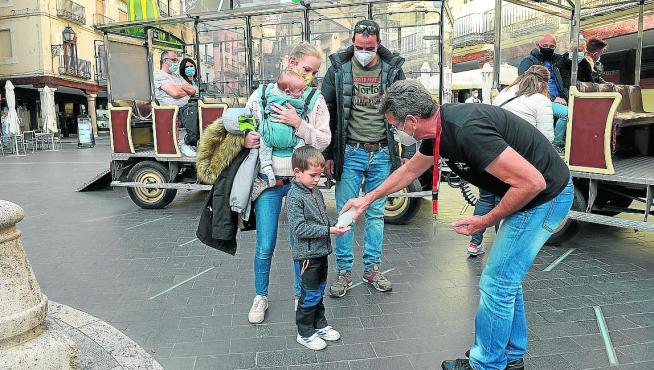 Los turistas limpian sus manos antes de subir al tren turístico en la plaza del Torico de Teruel.
