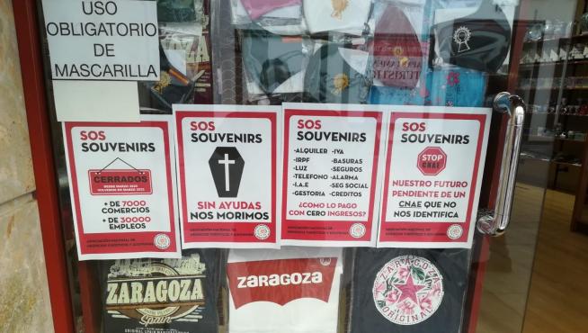 Carteles denunciando la difícil situación económica que atraviesa el sector, en el escaparate de una tienda de Zaragoza.
