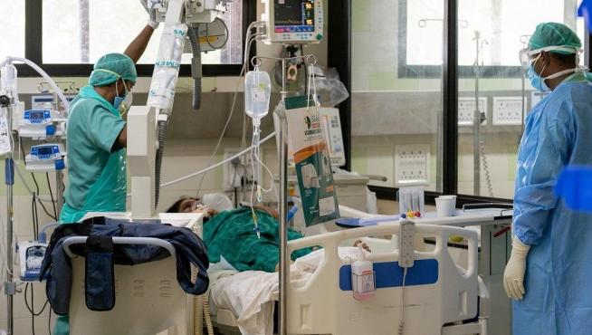 Dos médicos atienden a una paciente de covid en la India