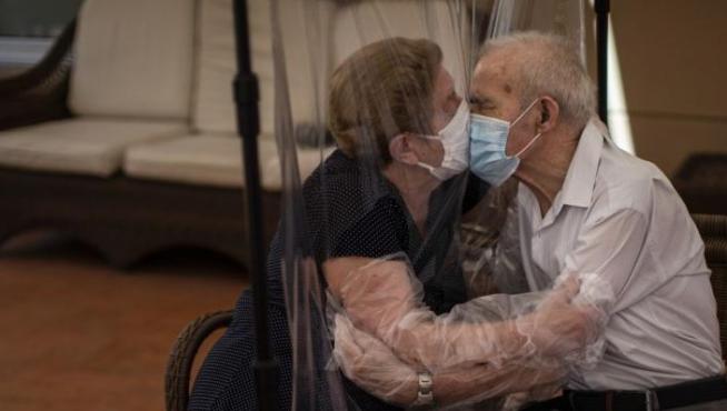 Agustina Cañamero, de 81 años, abraza y besa a su marido, Pascual Pérez, de 84, a través de un plástico en una residencia de Barcelona, el 22 de junio de 2020