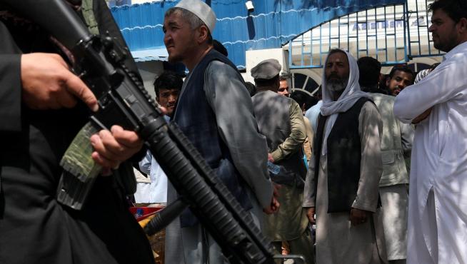 Un miembro de seguridad talibán vigila la fila de personas frente al Banco Azizi de Kabul, en Afganistán