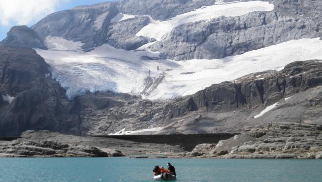 Varios investigadores se dirigen en una lancha, por el lago de Marboré, hacia el glaciar de Monte Perdido, en el Pirineo aragonés
