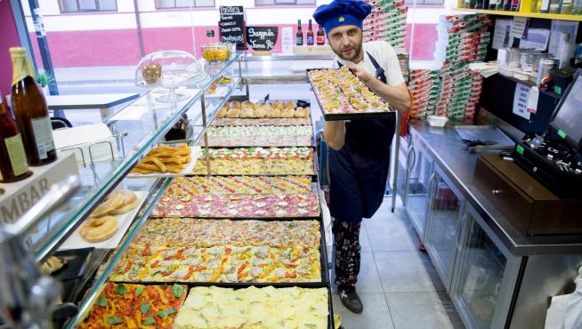 Cristian Georgita, con el mostrador repleto de pizzas al corte.