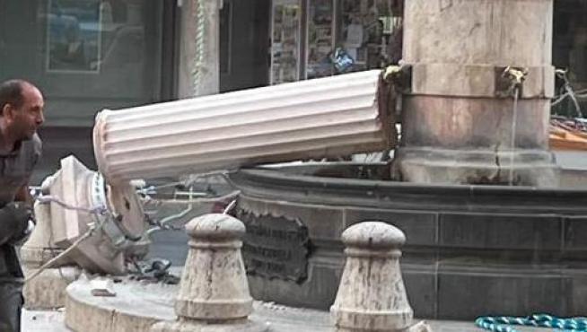 Un operario recoge la figura del Torico del suelo tras haberse desplomado la columna de la fuente.
