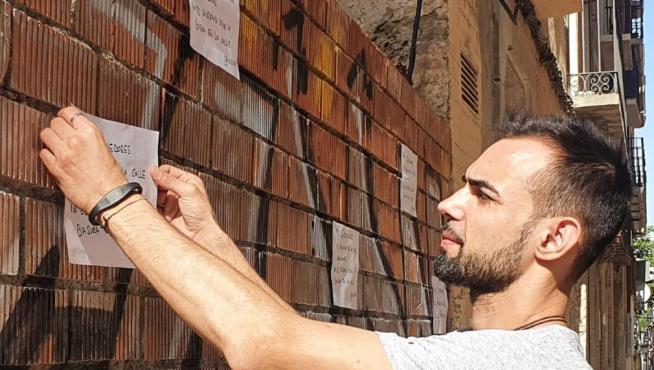 Caio Machado, colocando un cartel en la pared de la tapia ubicada en el solar del número 11 de la calle Casta Álvarez de Zaragoza