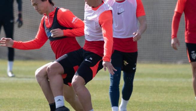 Kento Hashimoto trata de proteger el balón de la presión del futbolista del filial Jaime Escario.