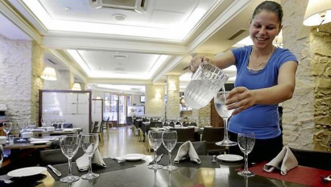 Mónica, camarera de la taberna Bílbilis, sirve agua del grifo en una copa.