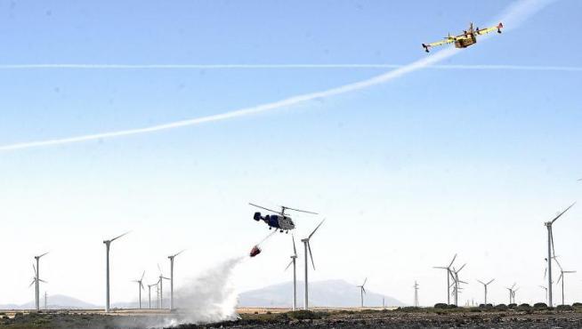 Un helicóptero echa agua sobre las llamas mientras un hidroavión sobrevuela la zona del incendio.