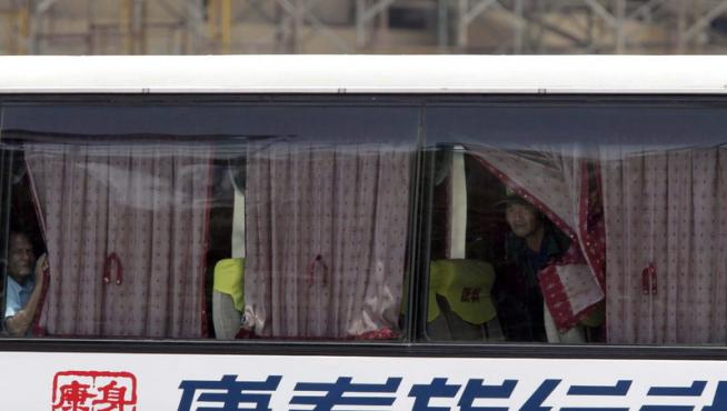 Varios rehenes miran por la ventana del autobús.