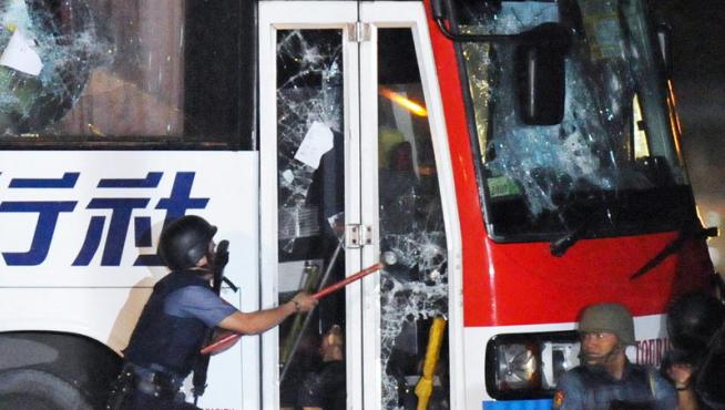 Un policía rompe el cristal de la puerta del autobús durante el tiroteo.
