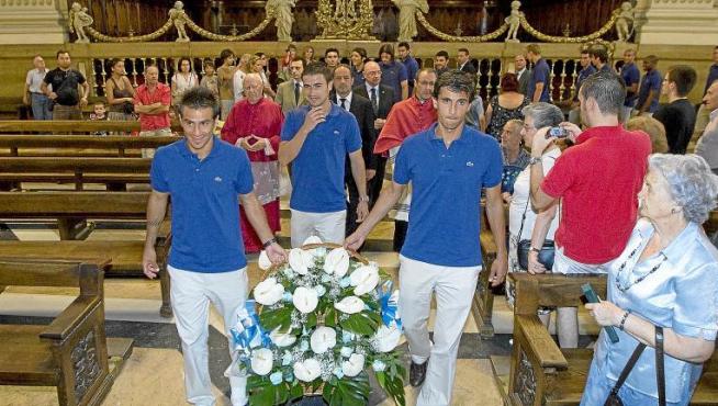 Los capitanes del Real Zaragoza, Gabi, Jorge López y Poncio, seguidos por la directiva y el capellán, llevan las flores al altar.
