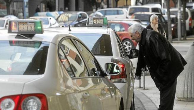 Un cliente se dispone a subirse a un taxi en la parada de la estación Intermodal de Huesca.