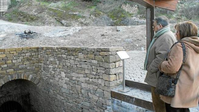Unos visitantes observan la entrada al pozo moro, sobre la que se ha construido una pérgola.