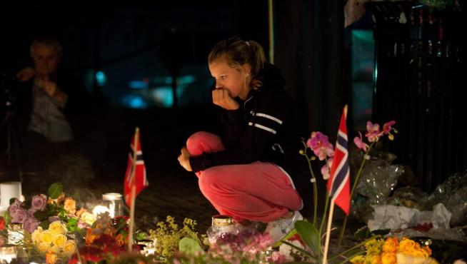 Una mujer permanece frente a las ofrendas dejadas en una iglesia de Oslo