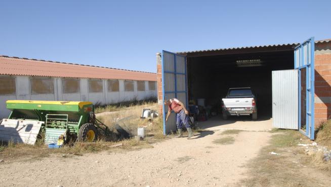 El propietario de un tractor robado abre las puertas de la cochera de donde fue sustraído.